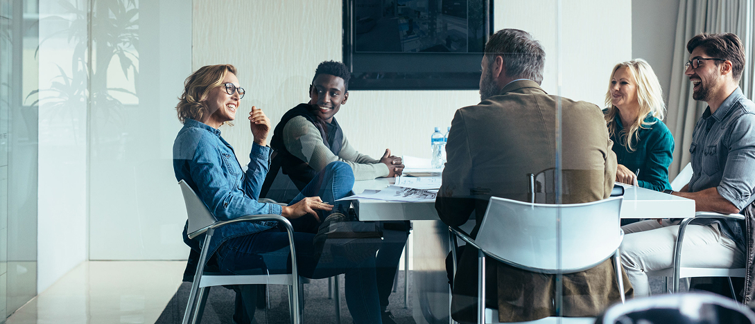 people around a meeting room table smiling at each other